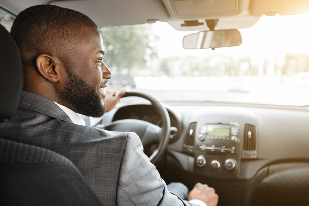Achteraanzicht van vrolijke zwarte zakenman rijden auto - Foto, afbeelding
