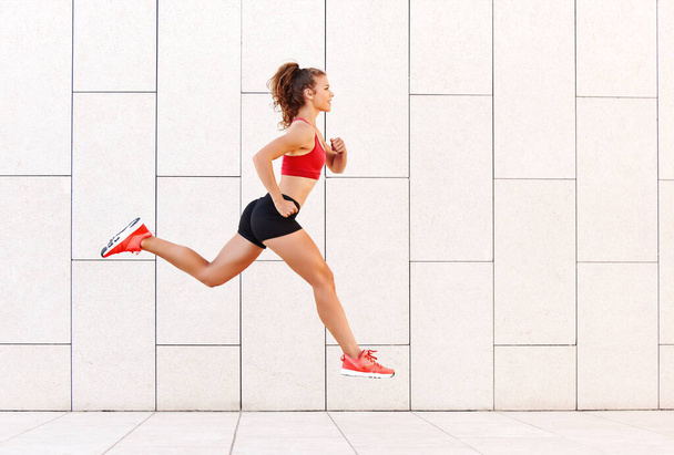Koncepcja sukcesu sportowego. silna młoda kobieta biegnie i skacze wysoko do zwycięstwa na tle miasta wal - Zdjęcie, obraz