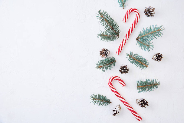 Composición navideña. Decoración hecha de ramas de abeto, conos de pino y dulces sobre fondo blanco - Foto, imagen