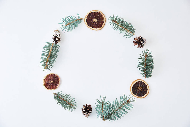 Christmas composition. Wreath made of fir tree branches and festive pine cones on white background, top view - Foto, Imagem