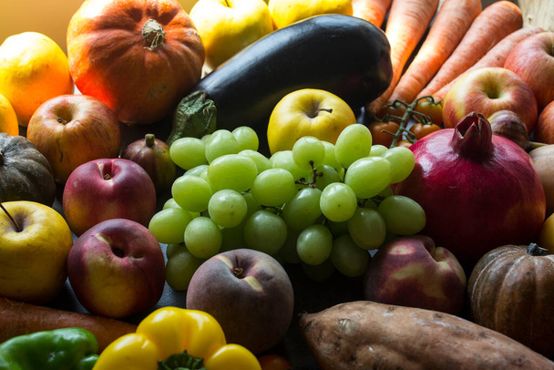 Fruits et légumes frais d'automne sur une table. Photo de dessus de grenades, raisins, citrouille, pommes et carottes.  - Photo, image