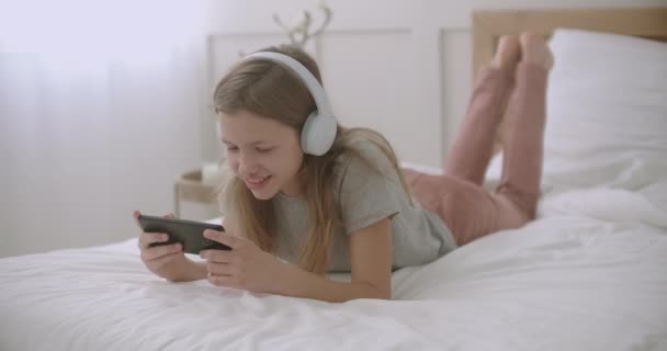 školní dívka používá aplikaci v smartphonu, leží v ložnici a mluví, volný čas dětí o víkendu - Záběry, video