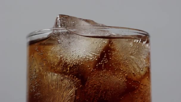 Κοντινό πλάνο φυσαλίδες cola και παγάκια σε διαφανές γυαλί - Πλάνα, βίντεο