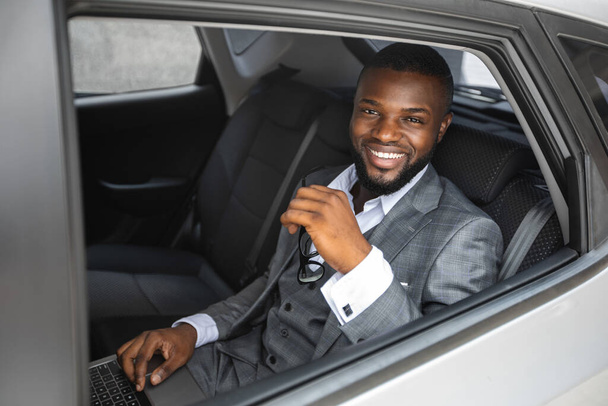 Rich african american businessman smiling through car window - Foto, Bild