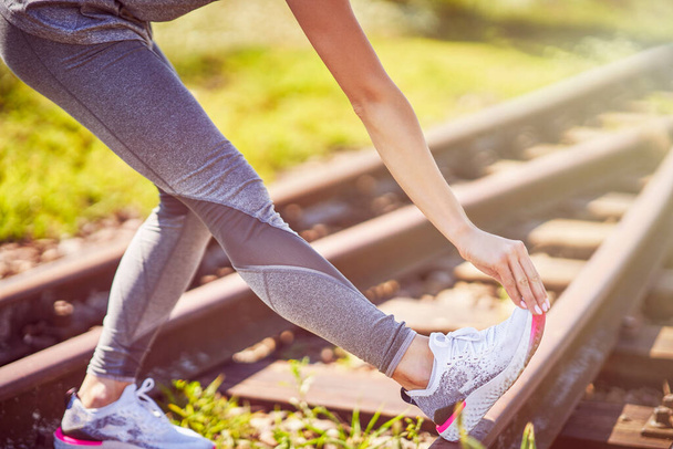 Midsection of female runner holding twisted ankle - Valokuva, kuva