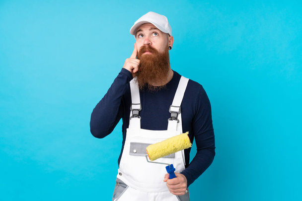 Живописець з довгою бородою над ізольованим синім тлом думаючи про ідею
 - Фото, зображення