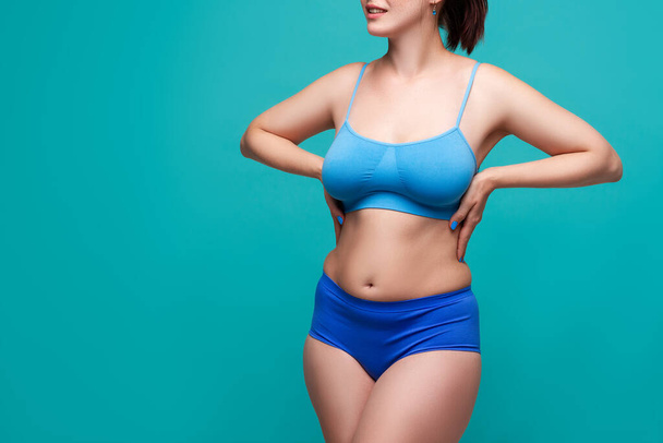 Plus size model in blue underwear on turquoise background, body positive concept - Zdjęcie, obraz