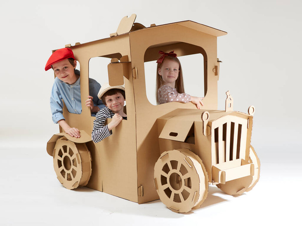 Creative children plays in cardboard car playhouse. - Foto, imagen