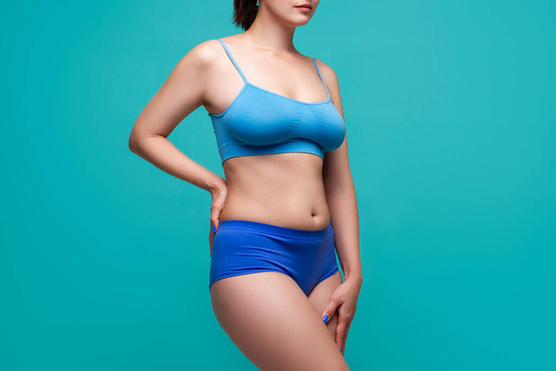 Beautiful sexy woman in blue underwear on turquoise background, perfect female body, studio shot - Фото, изображение