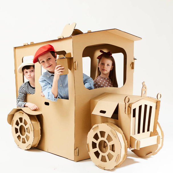 Creative children plays in cardboard car playhouse. - Valokuva, kuva