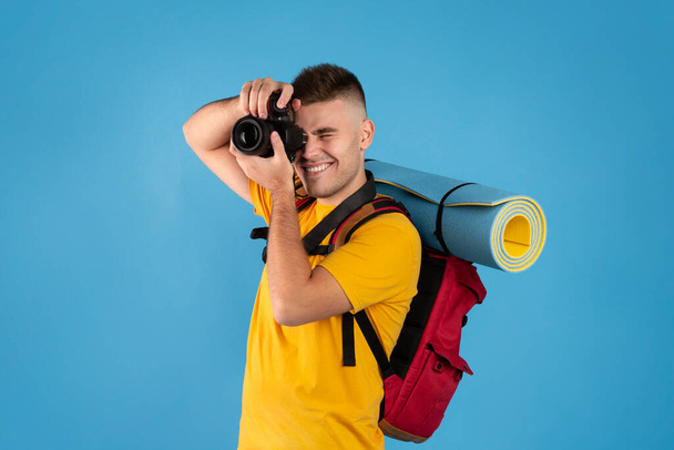Happy young traveler with backpack and camera ready to take photos on blue background - Fotografie, Obrázek