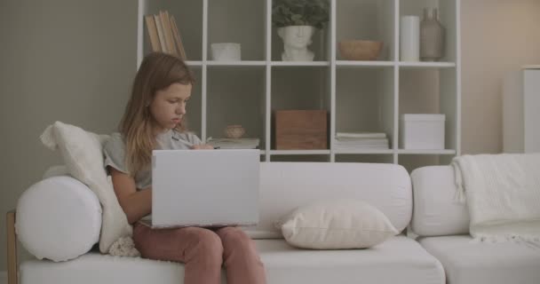 маленька дівчинка працює з блокнотом і малює в книзі вдома, сидячи на дивані у вітальні на вихідних
 - Кадри, відео