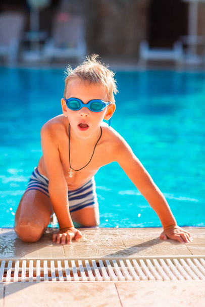 Cute happy little boy in goggles swimming and snorking in the swimming pool - Photo, Image