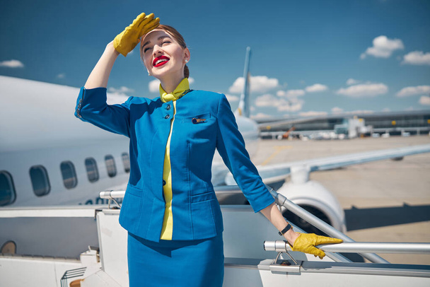 Прекрасная юная стюардесса, стоящая на лестнице самолета - Фото, изображение