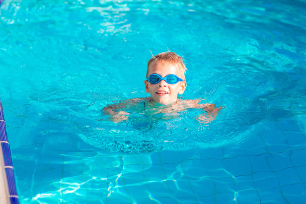 Cute happy little boy in goggles swimming and snorking in the swimming pool - Foto, imagen