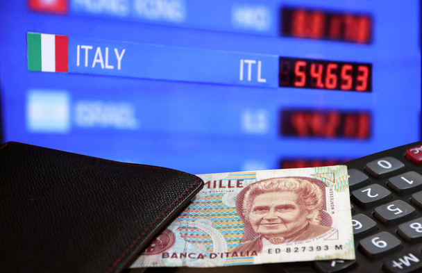 One thousand Lire of Italy banknote with black wallet on the calculator with digital board of currency exchange money background, Lire Italia money the concept of finance. - Photo, Image