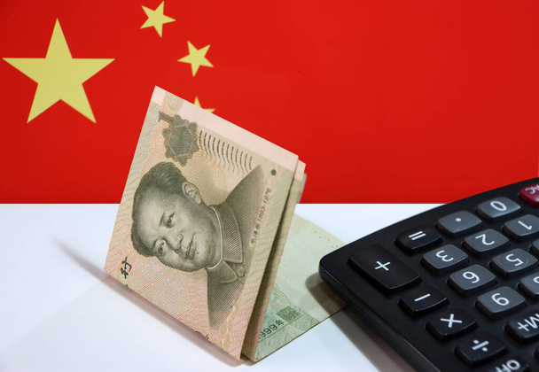 Un billet de banque yuan de Chine et calculatrice sur le plancher blanc avec le fond du drapeau de la nation chinoise, le concept de la finance. - Photo, image