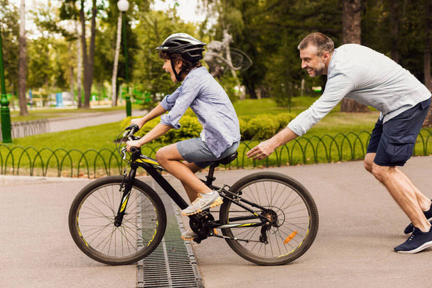 Zoon leren fietsen met zijn gelukkige vader - Foto, afbeelding