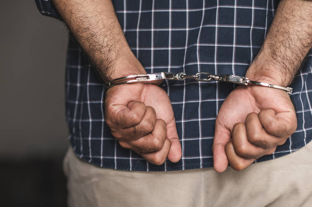 Gevangene man in de gevangenis met handboeien. close-up geboeid in handen. - Foto, afbeelding