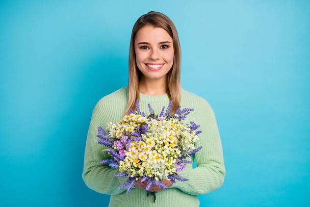 Close-up portrait of her she nice-looking attractive lovely cute winsome cheerful cheery girl holding in hands wild flowers isolated on gray bright vivid shine vibrant blue color background - 写真・画像