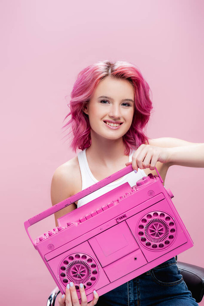 junge Frau mit buntem Haar hält bemaltes Tonbandgerät isoliert auf rosa - Foto, Bild