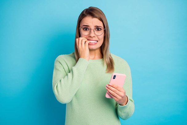 Close-up portrait of her she nice-looking attractive lovely charming pretty terrified girl using digital gadget biting nail worrying fail isolated over bright vivid shine vibrant blue color background - Fotografie, Obrázek