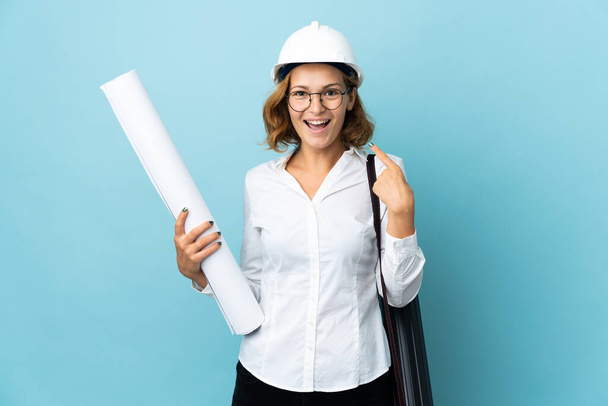 Young architect Georgian woman with helmet and holding blueprints over isolated background giving a thumbs up gesture - Photo, image