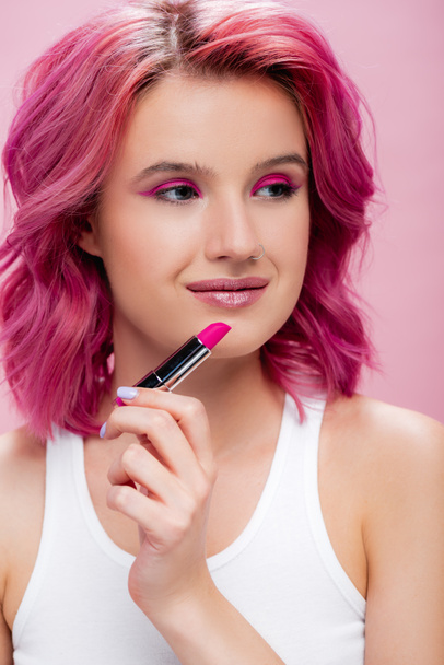 junge Frau mit bunten Haaren hält Lippenstift auf rosa - Foto, Bild