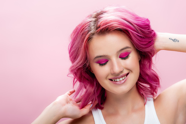 jovem com cabelo colorido e maquiagem sorrindo isolado em rosa - Foto, Imagem