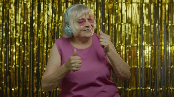 Anciana mayor baila, escucha música en los auriculares. Relajarse, disfrutar, divertirse, sonreír - Foto, Imagen