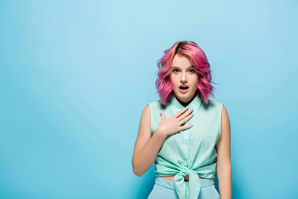 surprised young woman with pink hair and open mouth on blue background - Photo, Image