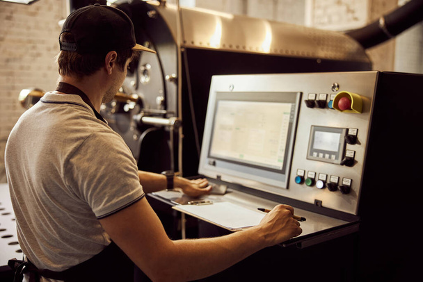 Trabajador masculino usando máquina de tostado de café industrial - Foto, imagen
