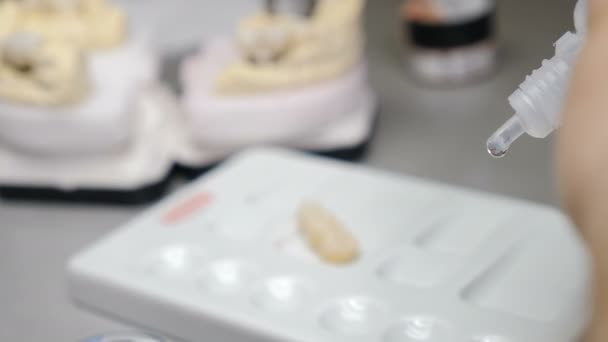 Technik dentystyczny pracujący z koronami ceramicznymi w laboratorium stomatologicznym. Technik pracujący nad nowymi zębami, przygotowujący się do nałożenia koloru na cyrkon. 4 tys. wideo - Materiał filmowy, wideo
