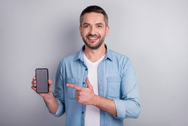 Close-up portrait of his he nice attractive content cheerful cheery guy demonstrating new cool digital device ad advert modern technology isolated over gray light pastel color background - Foto, Bild