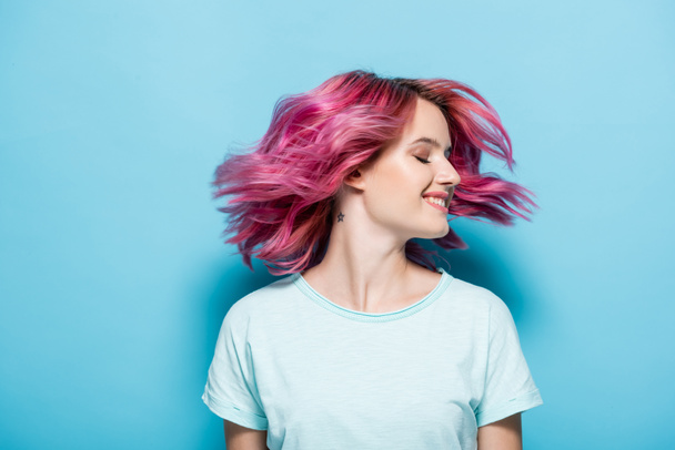 giovane donna che agita i capelli rosa su sfondo blu - Foto, immagini