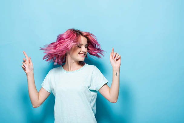 young woman waving pink hair on blue background - Foto, afbeelding