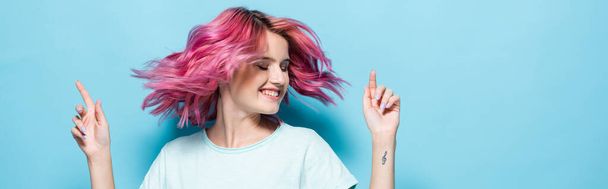 young woman waving pink hair on blue background, panoramic shot - Foto, afbeelding