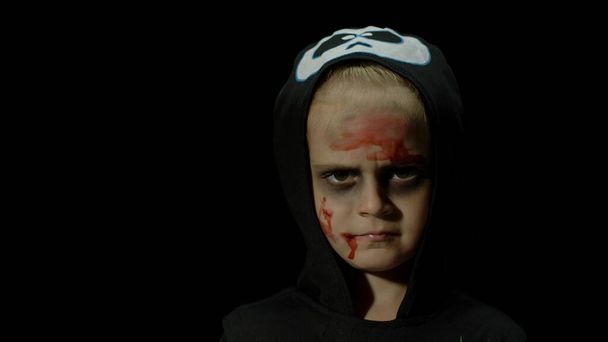 Halloween, naštvaná holka s krvavým make-upem na obličeji. Dítě převlečené za strašidelnou kostru, pózuje, dělá obličeje - Fotografie, Obrázek