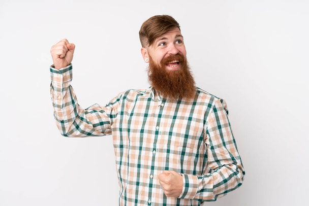 Homme rousse à longue barbe sur fond blanc isolé célébrant une victoire - Photo, image