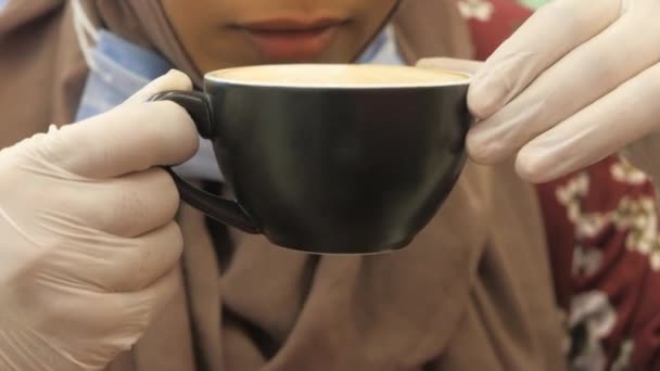 naiset lääketieteellisissä käsineissä juomassa kahvia kahvilassa. - Materiaali, video