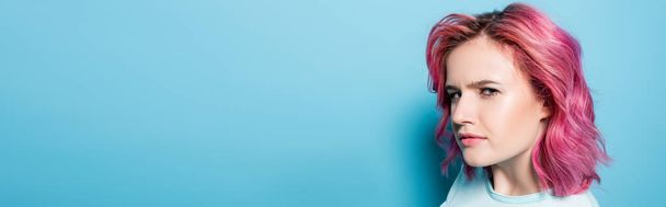 tense young woman with pink hair on blue background, panoramic shot - Zdjęcie, obraz