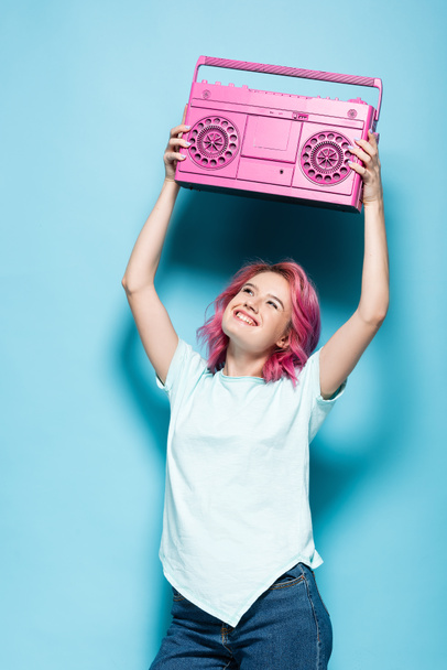 junge Frau mit rosafarbenen Haaren mit Vintage-Tonbandgerät auf blauem Hintergrund - Foto, Bild