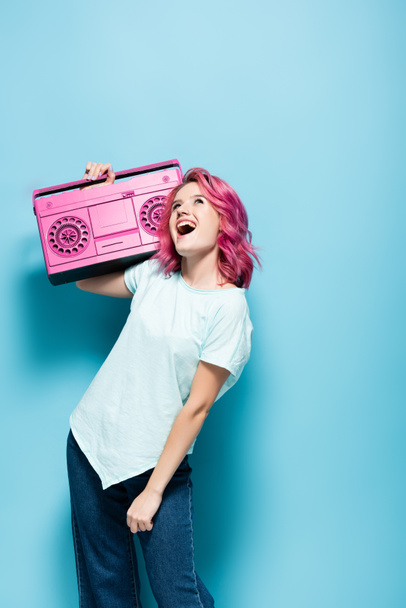 mladá žena s růžovými vlasy držení vinobraní magnetofon na modrém pozadí - Fotografie, Obrázek