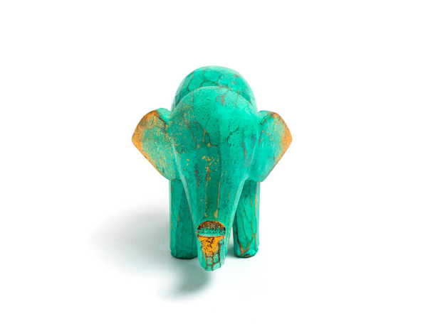 Figurine of a green wooden elephant with gilding isolated on white background. Decorative figurine of an elephant, hand carved wooden model of an elephant. Statuette, toy, souvenir from Asia. - Photo, Image