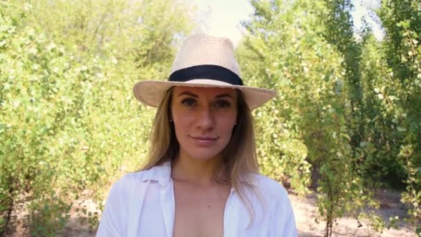 Ritratto di giovane donna in cappello sulla natura tra fogliame - Filmati, video