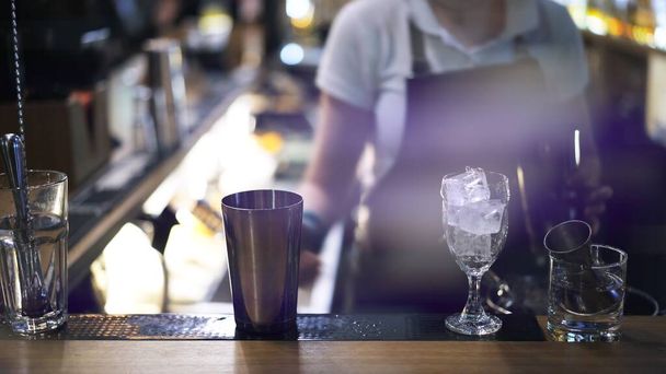Metal cups and glasses on bar counter on background of bartender  - Foto, Bild