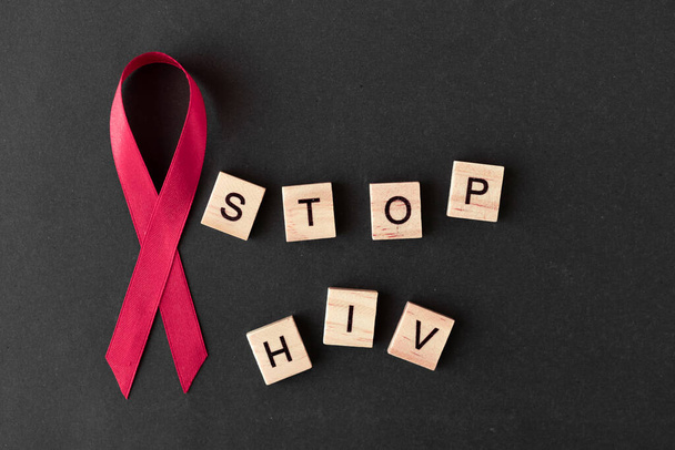 Red ribbon. Concept for World AIDS Day. black background, copy space. words stop HIV - Foto, Bild