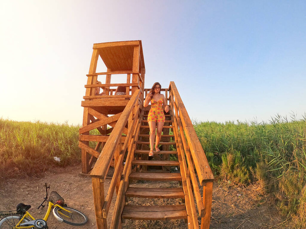 Женщина в поле зрения. Девушка спускается по лестнице точек зрения и молодая милая девушка смотрит на природу взгляды на закате - Фото, изображение