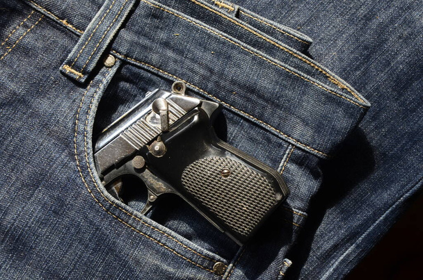 Пістолет у кишені джинсових штанів, що борються завантажено. Пістолет у кишені джинсів
. - Фото, зображення