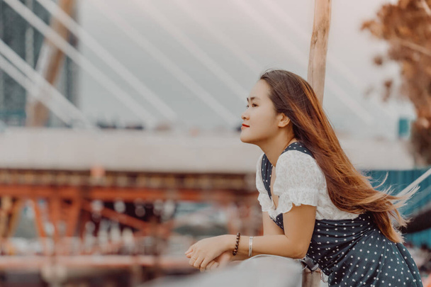 girl standing by the riverbank admiring the scenery and a new cable-stayed bridge is building connecting Thu Thiem peninsula and District 1 across the Saigon River in blurred background.Travel concept - Photo, Image